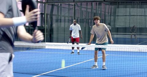 Energetic Padel Players Competing on Modern Blue Indoor Court