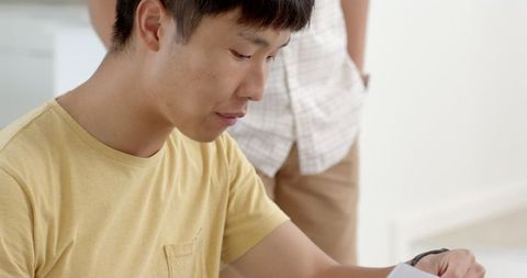 Asian teenager focused on tasks at home in casual setting