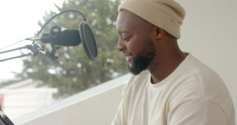 African american podcaster recording voiceover in home studio with microphone and tablet