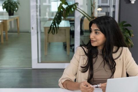 Professional woman preparing for meeting with laptop and notes in modern coworking office