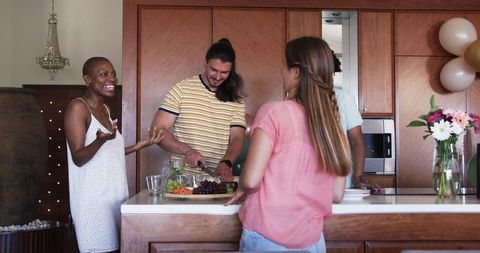 Friends Engaging in Conversation While Cooking in Modern Kitchen