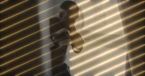 Boxer Practicing Punches in Dimly Lit Gym through Blinds