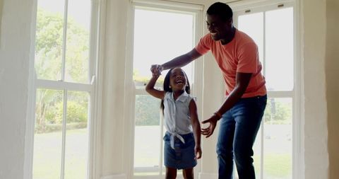 Father Joyfully Spinning Daughter in Bright Sunlight