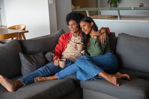 Happy couple relaxing with coffee on comfortable sofa