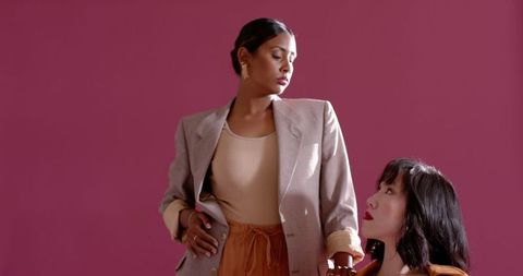 Professional female colleagues posing against magenta background