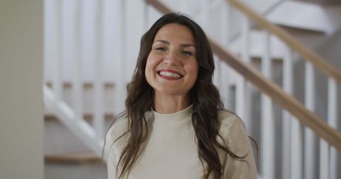 Cheerful caucasian woman smiling indoors on wooden staircase