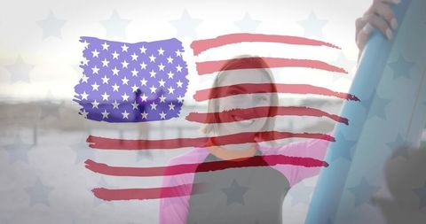 Smiling female surfer holding surfboard with painterly american flag overlay on beach