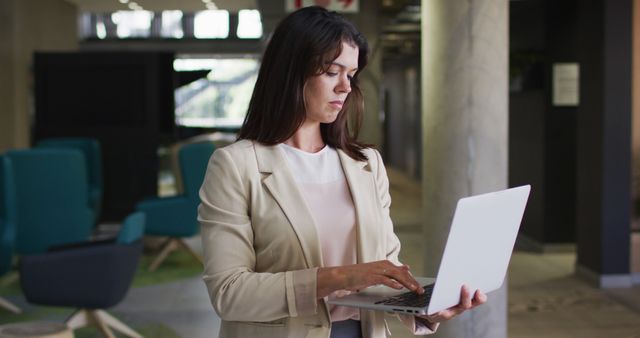 Business woman is using laptop in modern office space. Ideal for corporate presentations, technology-related articles, and business training materials.