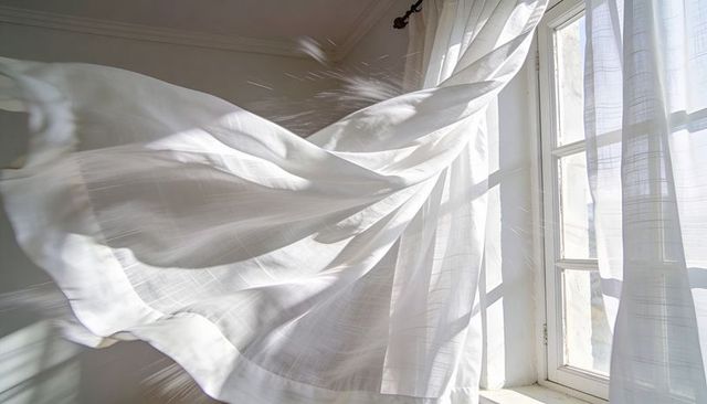 Sunlit sheer curtains billowing in breeze through window casting soft geometric shadows
