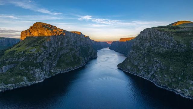 Sunlit cliffs framing serene fjord channel at golden hour