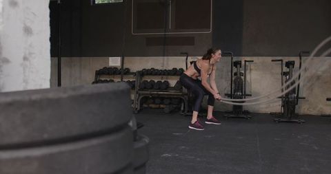 Motivated Woman Intense Battle Rope Workout in Modern Gym