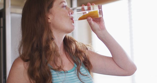 Caucasian woman drinking healthy drink in kitchen. staying at home in isolation during quarantine lockdown.