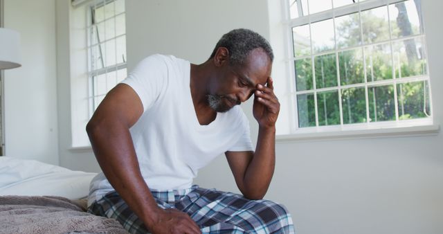 Senior african american man with headache sitting on bed holding head - Download Free Stock Photos Pikwizard.com