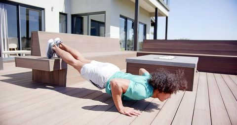 Fit man performing bench push-ups in backyard for strength and balance training