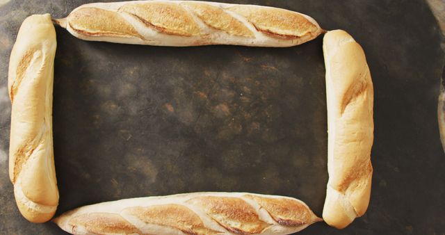 Image of four baguettes forming rectangle on a black surface. food, cuisine and catering ingredients.