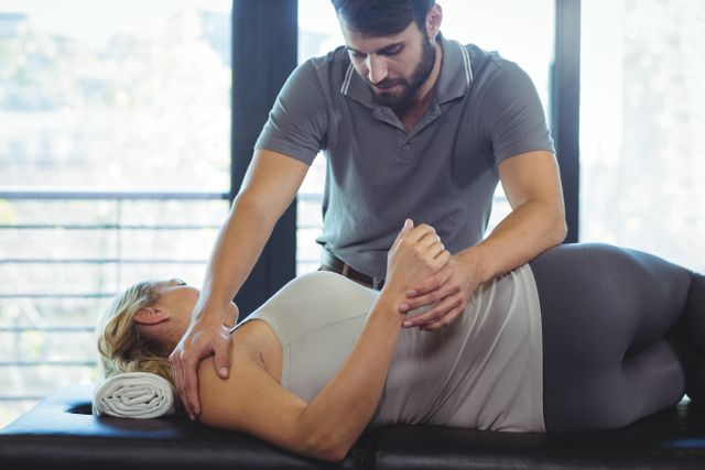 Physiotherapist providing shoulder therapy to a woman in a clinic. Ideal for use in healthcare, medical, and wellness contexts. Can be used to illustrate physical therapy treatments, patient care, and rehabilitation processes.