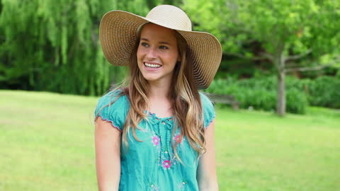 Smiling Woman in Sun Hat Enjoying a Sunny Day in Park