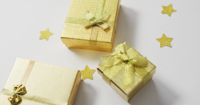Golden gift boxes adorned with glittery bows and scattered star decorations. Ideal for depicting luxury and elegance in celebration events, festive seasons, or special occasions. Perfect for use in holiday promotions, gift wrapping ideas, and celebratory advertisements.