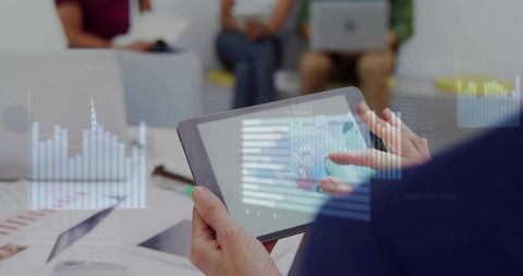 Analyzing tablet data visualizations during collaborative meeting in modern office lounge