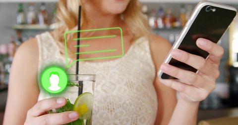 Woman checking smartphone at bar while receiving neon chat notification over cocktail
