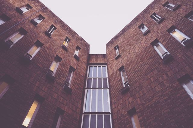 This image features the symmetrical perspective of a brick building with multiple windows, creating an intriguing urban and geometric pattern. Ideal for architectural presentations, urban design inspiration, real estate marketing materials, or modern architecture blogs.