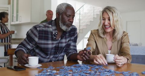 Senior friends completing puzzle over tea at home