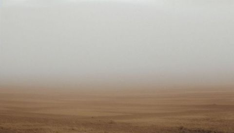 Barren wind-sculpted desert plain fading into pale haze evoking solitude and minimalism