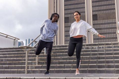 Urban duo balancing on one leg on city steps during outdoor workout and balance training