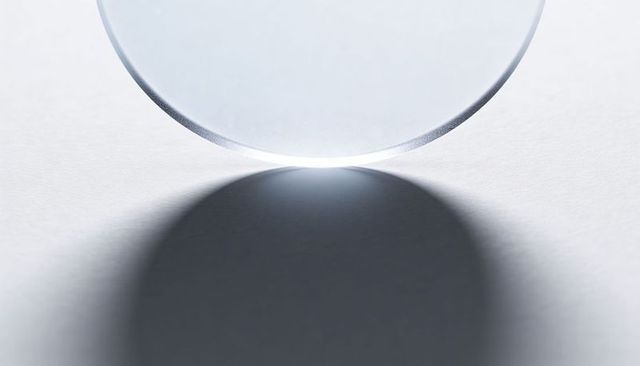 Glass Disc Resting on White Paper with Beveled Edge, High-key Glint and Soft Shadow