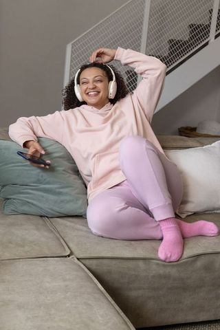 Smiling african american woman lounging on couch with headphones and smartphone