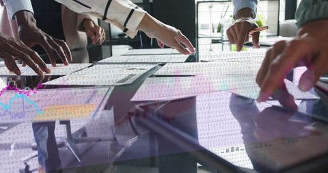 Business team collaborating on interactive touchscreen table analyzing data visualizations