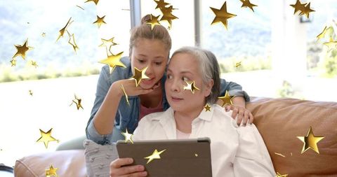 Grandmother and Granddaughter Sharing Tablet with Gold Star Overlay, Cozy Family Bonding