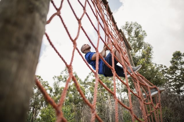 Fit man climbing a net during obstacle course in boot camp