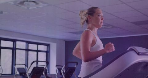 Determined woman running on treadmill in modern gym environment