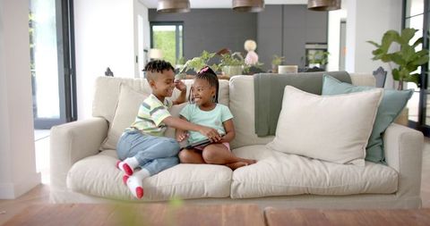 Happy siblings enjoying tablet activity in modern living room