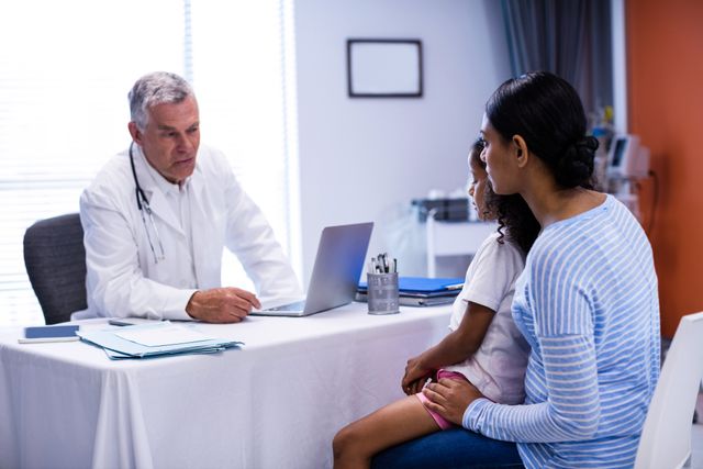 Doctor discussing health concerns with mother and child in a clinical setting. Ideal for illustrating medical consultations, healthcare services, pediatric care, family health, and doctor-patient interactions.
