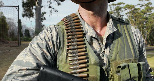 Uniformed Soldier Holding Gun with Ammunition Belt Over Shoulder in Outdoor Setting - Download Free Stock Images Pikwizard.com