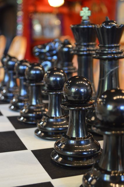 This close-up view of black chess pieces placed neatly on a chessboard can be used for themes involving strategy, competition, and intellectual pursuits. Suitable for illustrating board game-related content, educational materials about chess, or adding an element of sophistication to articles on strategic thinking and planning.