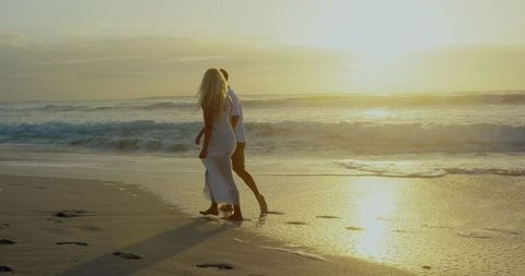 Romantic Couple Walking Hand in Hand on a Beach at Sunset - Download Free Stock Images Pikwizard.com