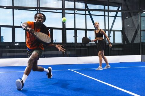 Diverse Friends Engaged in Dynamic Padel Match on Blue Court