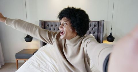 Man sitting on bed with outstretched arm in modern bedroom