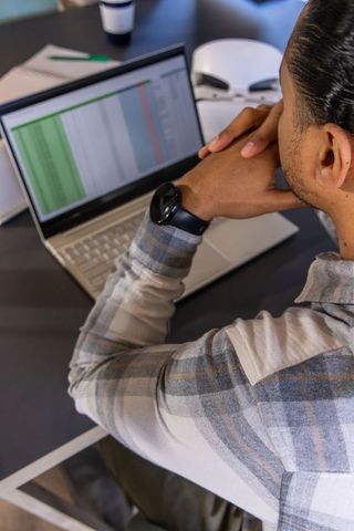 Young professional reviewing spreadsheet on laptop during focused remote work session