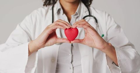 Female doctor holding red heart symbolizing heart health and compassionate care