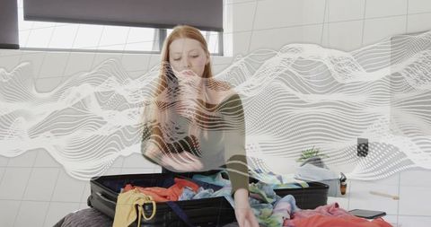 Young woman packing colorful clothes into suitcase on bed with soft abstract wave overlay