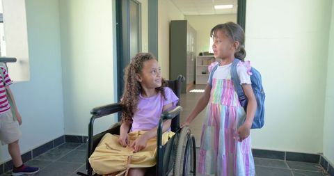Inclusive school friendship: african american girl in wheelchair with asian classmate