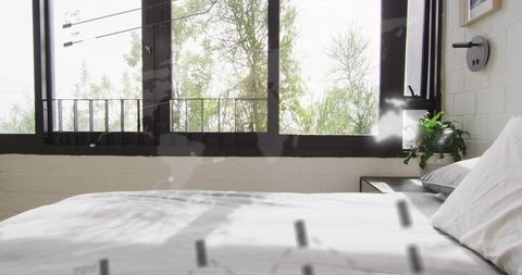 Casting serene shadows across white minimalist bed in modern bedroom with balcony view