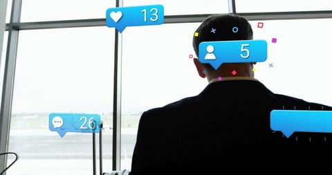 Business traveler checking mobile at airport terminal with social media engagement icons