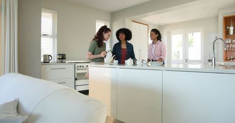 Multiracial Women Enjoying Relaxed Tea in Bright Kitchen
