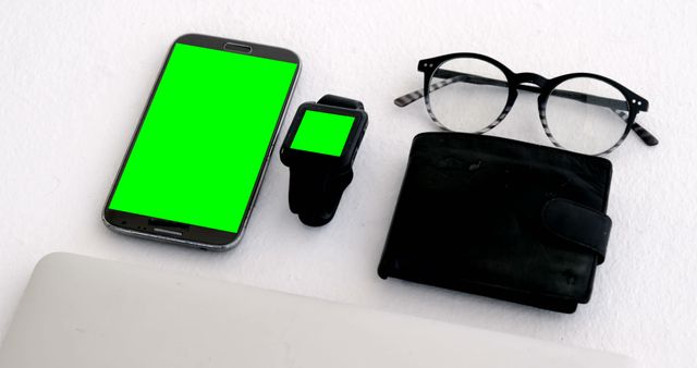 A smartphone, smartwatch with green screens, eyeglasses, and a wallet are neatly arranged on a surface, with copy space. These items represent everyday essentials for a modern professional or tech-savvy individual.