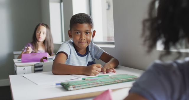Elementary school boy attentively studying in classroom setting, surrounded by peers. Perfect for educational materials, school websites, child development resources, or advertisements for educational programs.